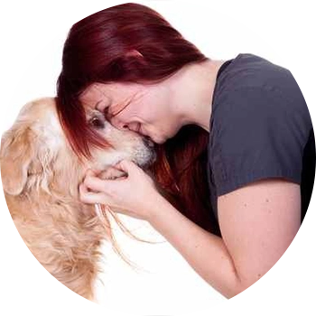 A woman holding onto her dog while she is kissing it.