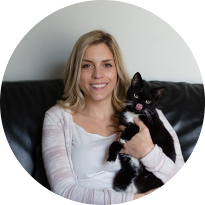 A woman holding a black and white cat.